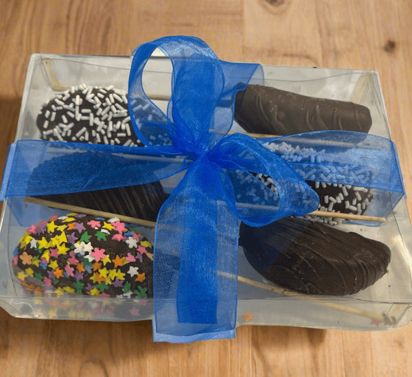 Chocolate Dipped Apple Sticks 6-pack in clear gift box with blue ribbon, featuring assorted toppings like sprinkles and chocolate drizzle.