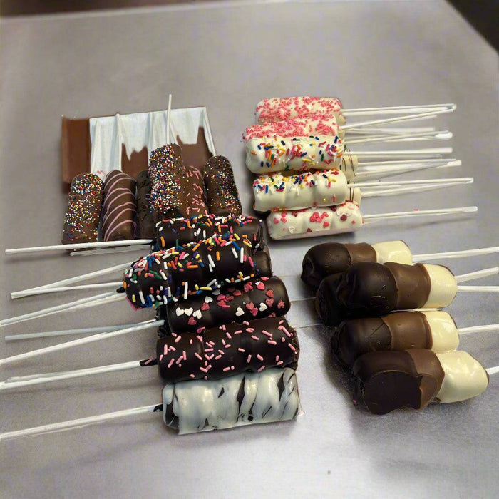 Variety of Passover chocolate-dipped marshmallow sticks arranged on a tray, featuring milk, dark, and white chocolate coatings.