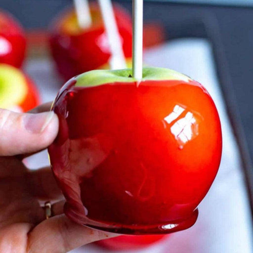 Classic Red Candy Apple with glossy red coating held by hand, showcasing nostalgic treat from the candy category.