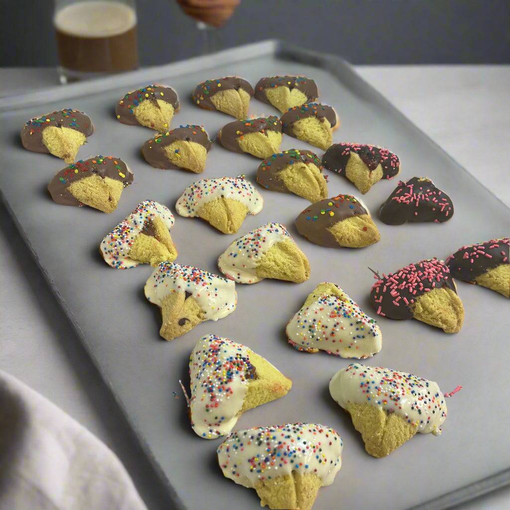 Tray of Hamantaschen -Chocolate-Dipped cookies in white and dark chocolate with sprinkles, a festive bakery item for Purim celebrations.