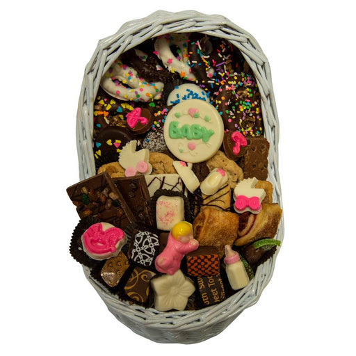 Top view of Baby Girl Bassinet Gift Basket showcasing hand-crafted chocolates, cookies, and candies in a reusable white wicker basket.