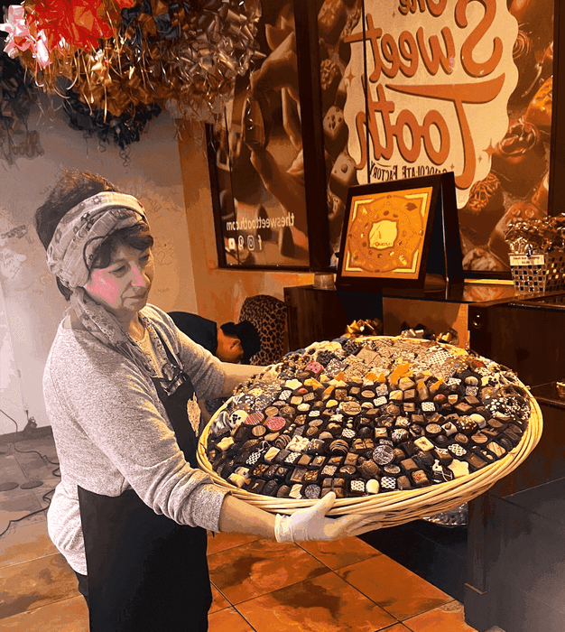 SUPREME - Congratulations large chocolate gift basket being held by a shop staff member, showcasing premium handcrafted confections.