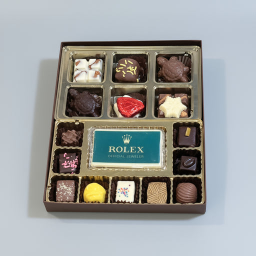 Box of assorted chocolates with a Rolex logo on a wooden surface