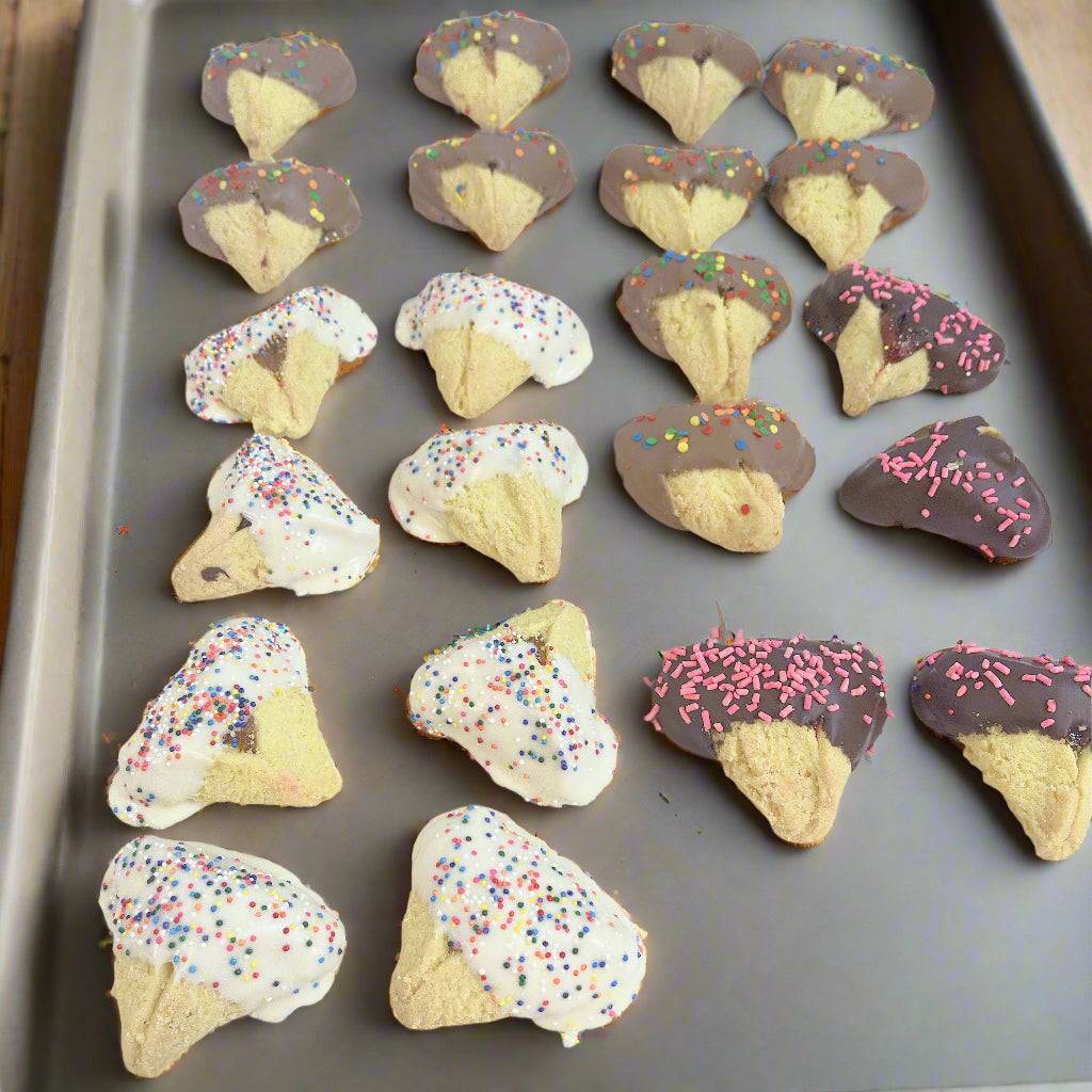 Tray of hamantaschen cookies dipped in white and dark chocolate with colorful sprinkles, perfect for Purim celebrations and gift baskets.