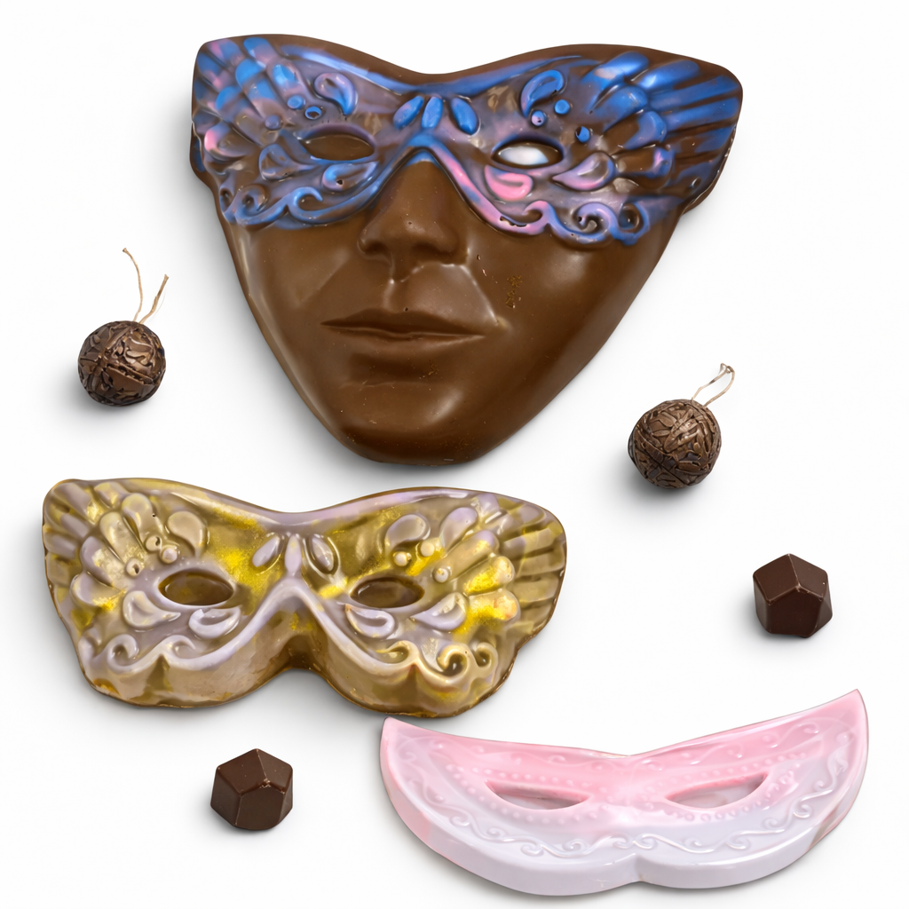 Three kosher chocolate masks in blue, gold, and pink with small chocolate pieces around on a white background.