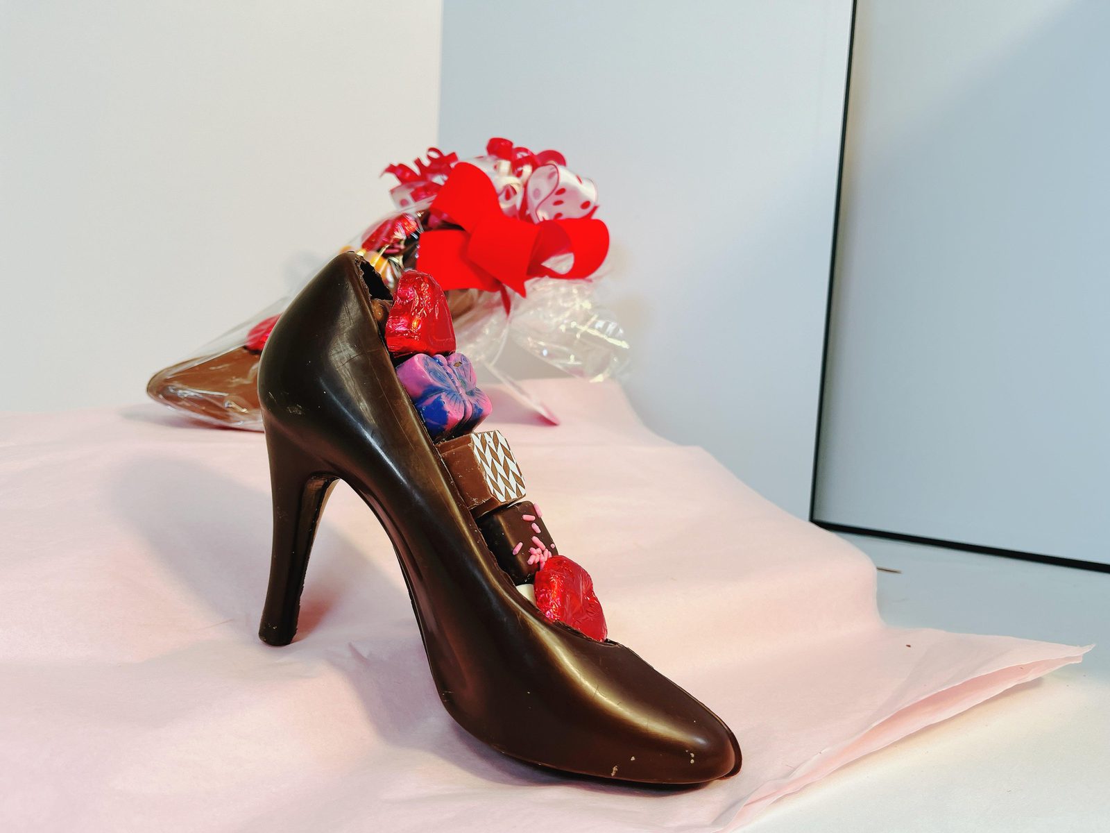 Dark chocolate high heel shoe packed with colorful truffles and heart-shaped chocolates, ideal for unique edible gifts.