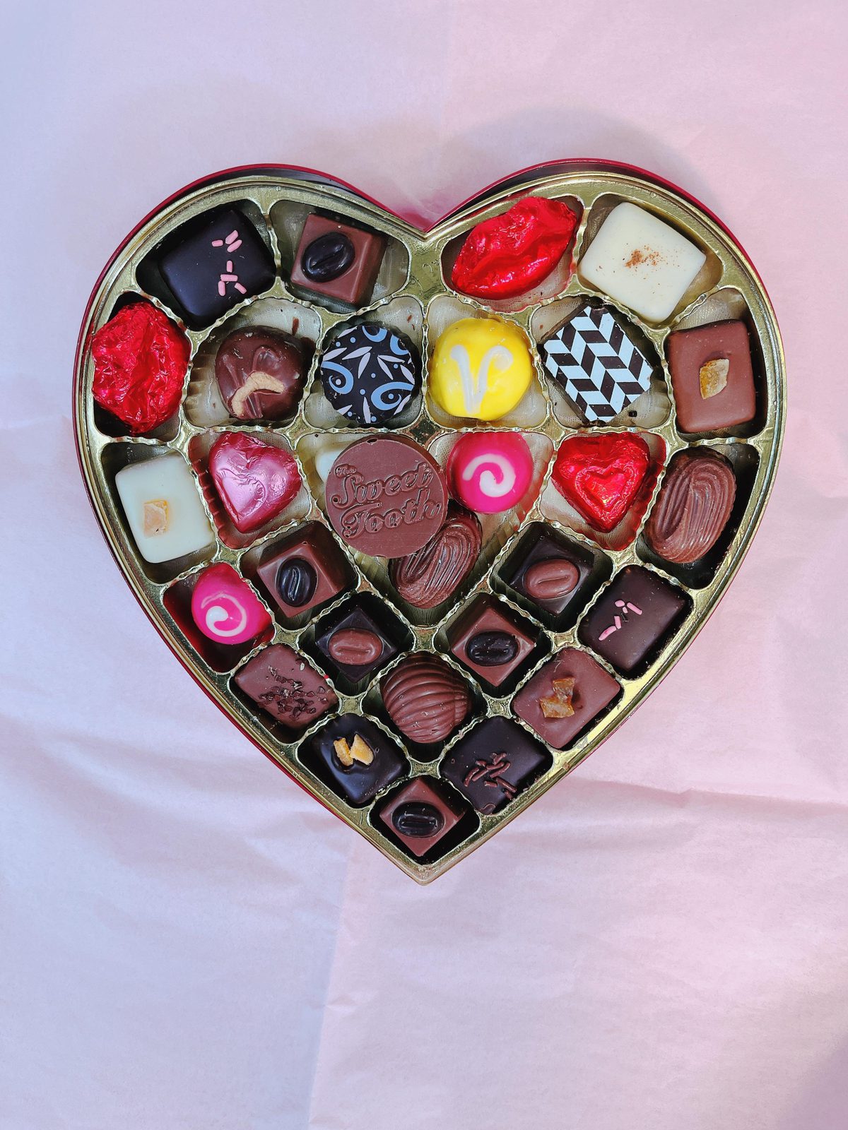 Top view of Heart-Shaped Box of Chocolates & Truffles featuring colorful chocolate-covered fruit and artisan truffles in gold tray.