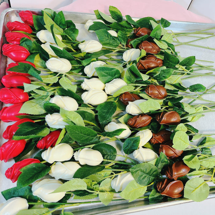 Tray of chocolate roses in red, white, and milk chocolate with green leaves, great for party treats or festive gift arrangements.