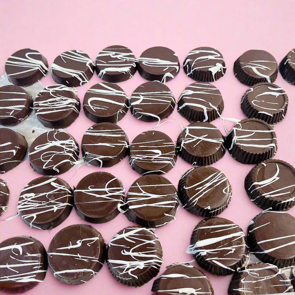 Round chocolate cups with white drizzle from SUPREME - Passover, a decadent treat for luxury food gift baskets.