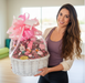 Woman holding a large gift basket bassinet with pink ribbons indoors.