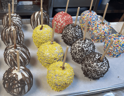 Assorted candy-coated apples on sticks displayed on a tray.