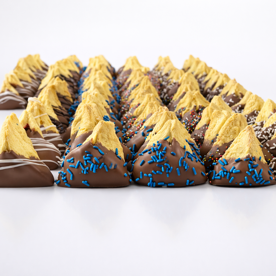 Freshly baked hamantaschen cookies dipped in white chocolate and drizzled with dark chocolate, cooling on a parchment-lined tray. Perfect for Purim celebrations.