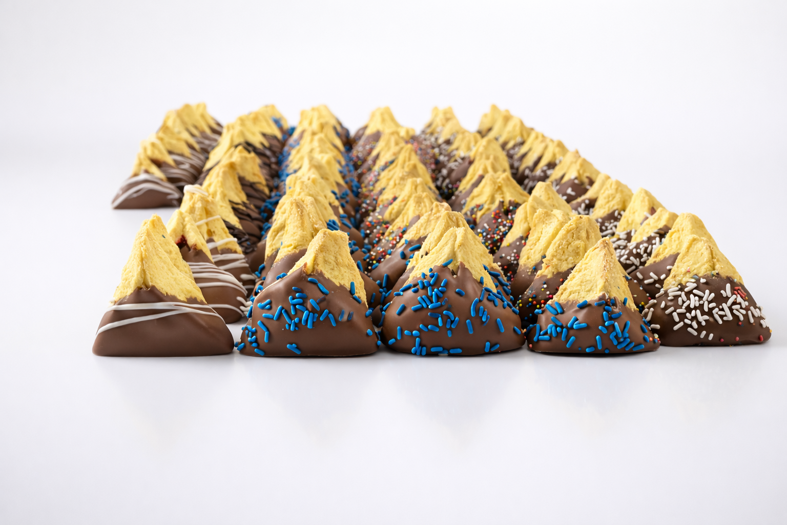 Freshly baked hamantaschen cookies dipped in white chocolate and drizzled with dark chocolate, cooling on a parchment-lined tray. Perfect for Purim celebrations.