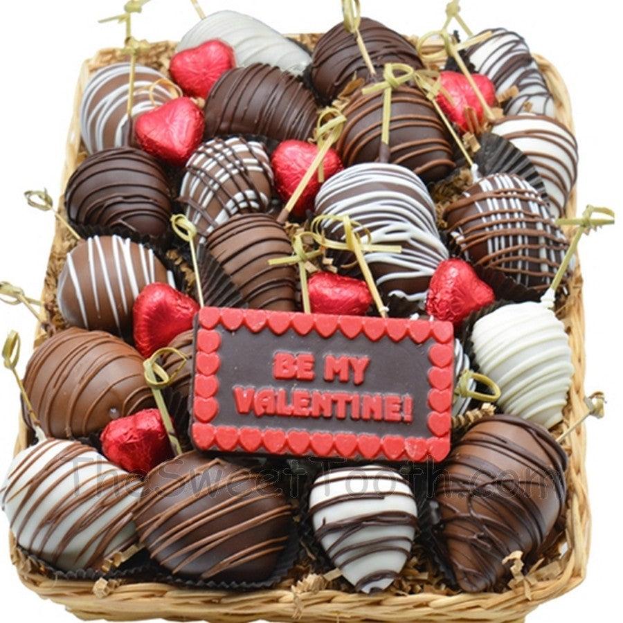 Chocolated dipped strawberries for Valentine's Day arranged in a festive basket with red heart candies and a 'Be My Valentine' chocolate plaque.