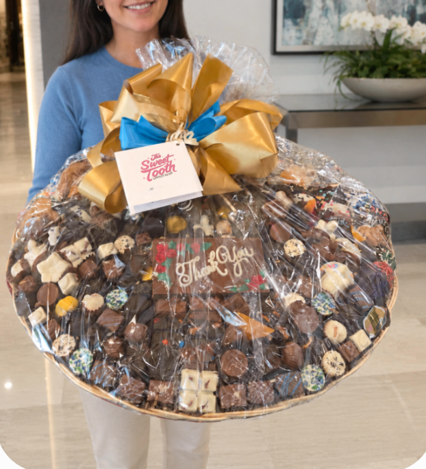 Customer holding an Ultimate chocolate gift basket wrapped in cellophane with a hand-tied bow